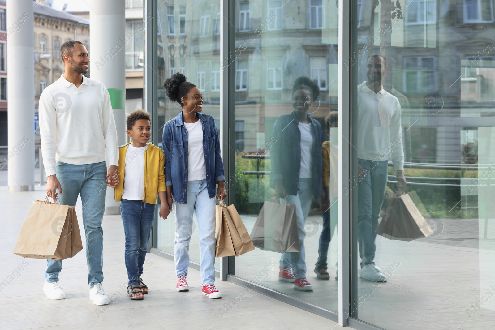 Photo of Family shopping. Happy parents and son with purchases near mall outdoors