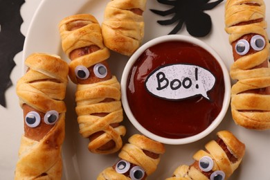 Photo of Tasty sausage mummies for Halloween party on plate, top view
