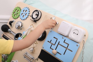 Photo of Little child playing with busy board indoors, closeup