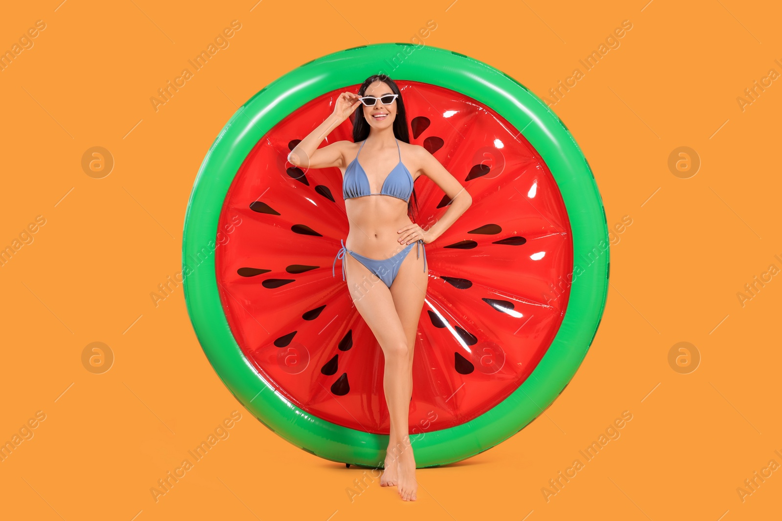 Photo of Happy young woman with beautiful suntan, sunglasses and inflatable mattress against orange background