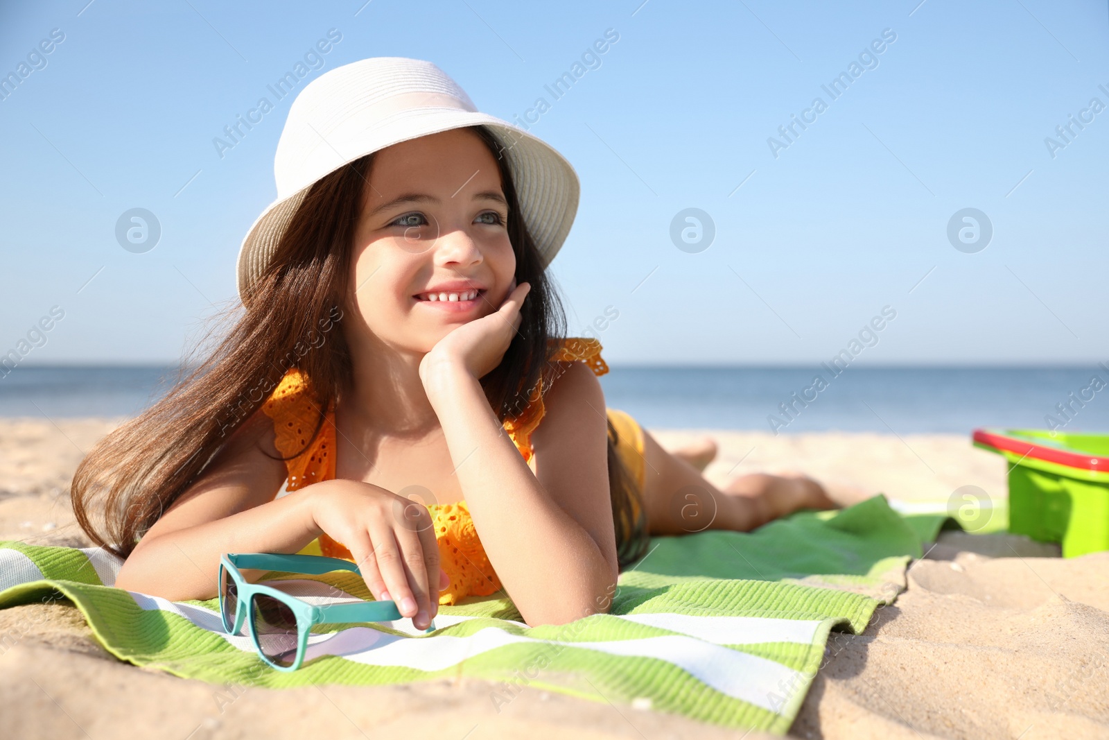 Photo of Cute little child lying at sandy beach on sunny day