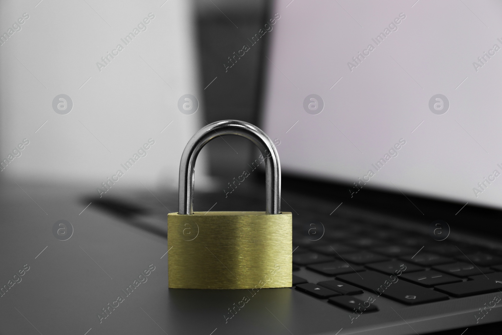 Photo of Cyber security. Metal padlock on laptop, closeup