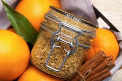 Jar of dried orange zest seasoning and cinnamon on fresh fruits, closeup