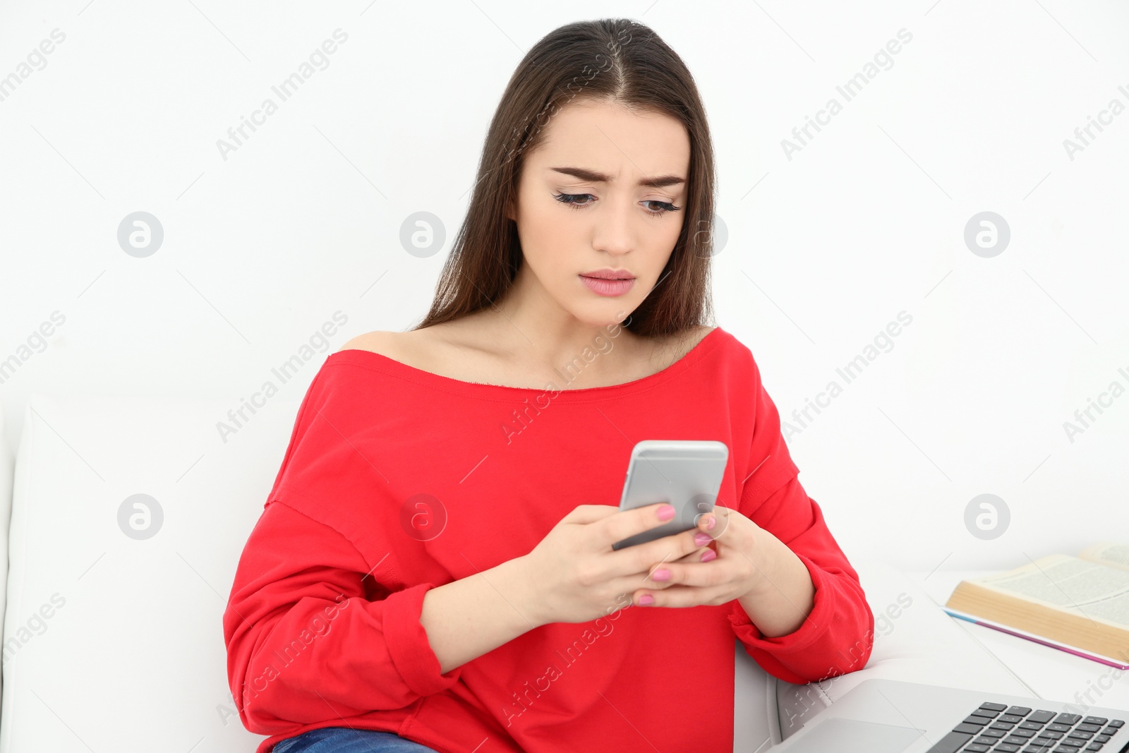 Photo of Young woman using mobile phone and laptop at home