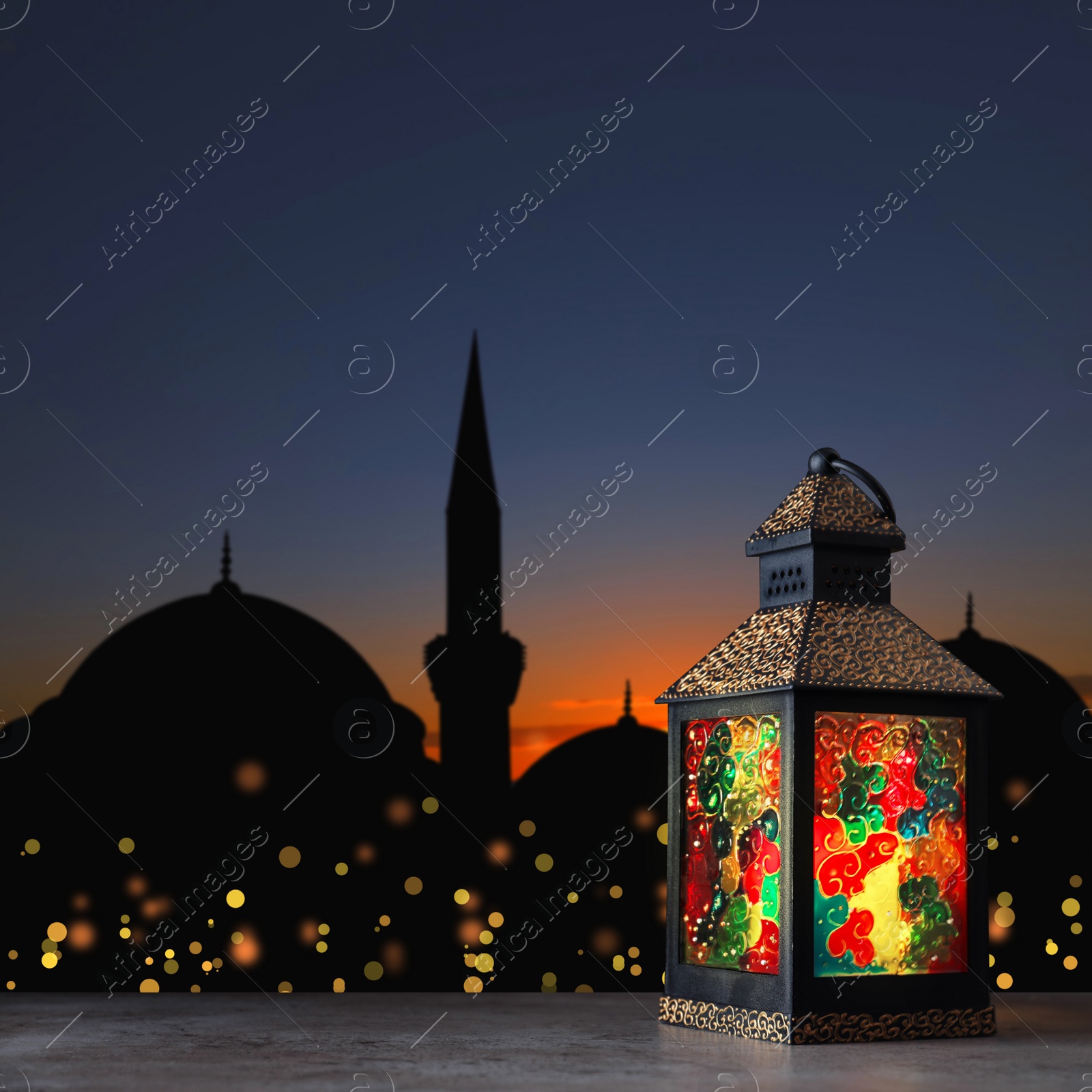 Image of Decorative Arabic lantern on stone surface and silhouette of mosque at sunset on background, space for text