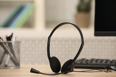 Photo of Headset and computer on table indoors. Hotline concept