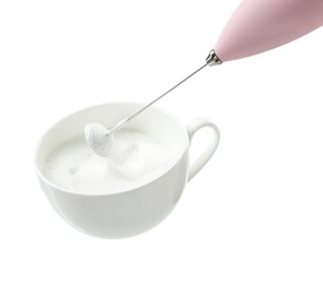 Photo of Whisking milk in cup with mini mixer (frother wand) isolated on white, closeup