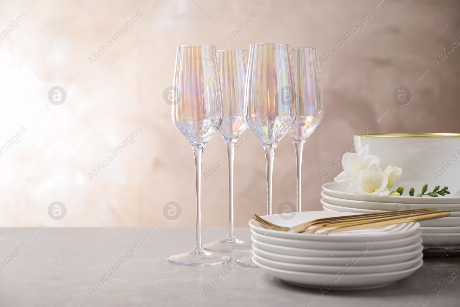 Photo of Set of glasses and dishes with flowers on light grey table