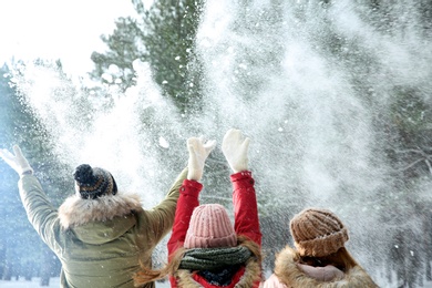 Happy family throwing snow in winter forest
