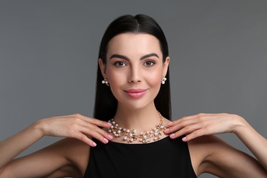 Photo of Beautiful young woman with elegant jewelry on dark grey background