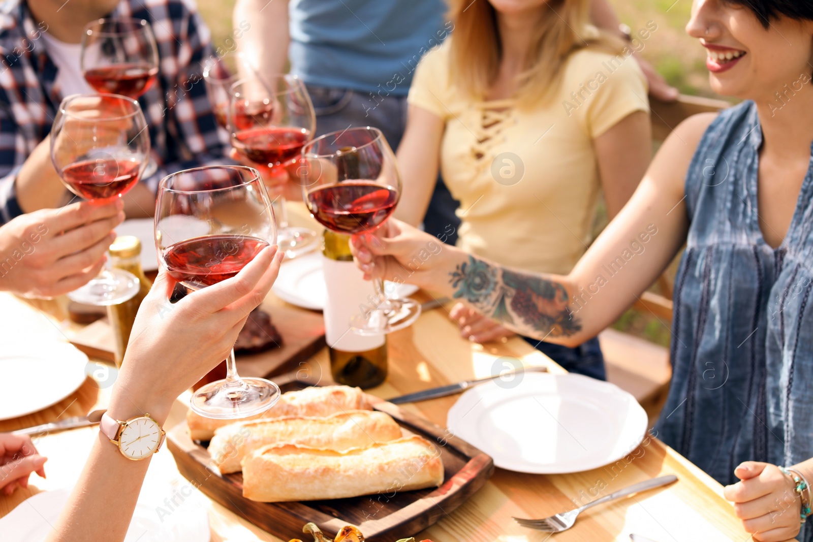 Photo of Young people with glasses of wine at table outdoors. Summer barbecue