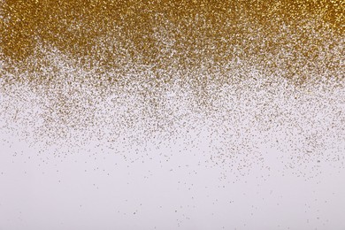 Photo of Shiny golden glitter on white background, top view