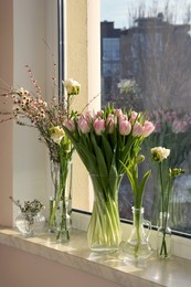 Photo of Many different spring flowers and branches with leaves on windowsill indoors