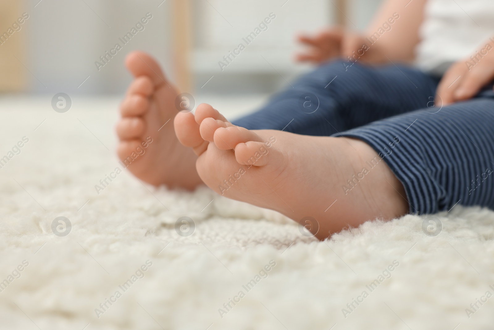 Photo of Baby sitting on soft carpet indoors, closeup