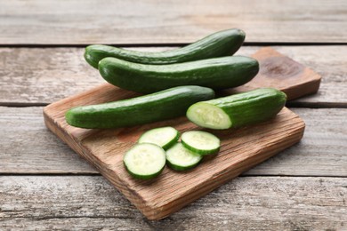 Photo of Whole and cut fresh ripe cucumbers on wooden table
