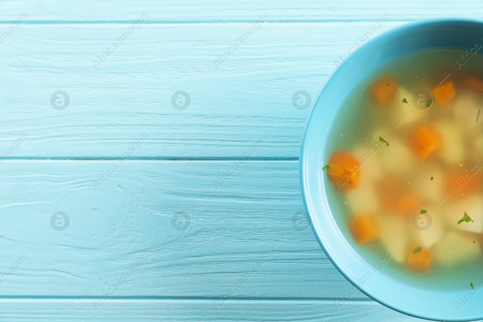 Photo of Bowl of fresh homemade soup to cure flu on wooden background, top view with space for text