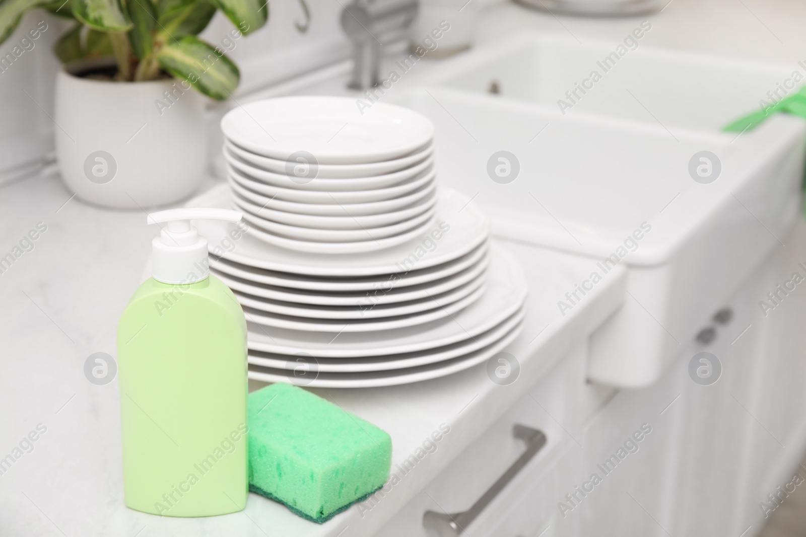 Photo of Clean dishes and cleaning product in stylish kitchen