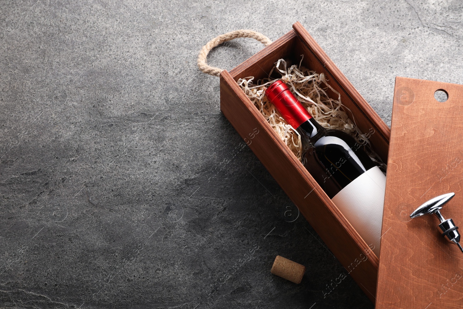 Photo of Bottle of wine in wooden box on dark textured table, above view. Space for text