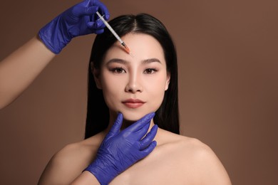 Photo of Woman getting facial injection on brown background