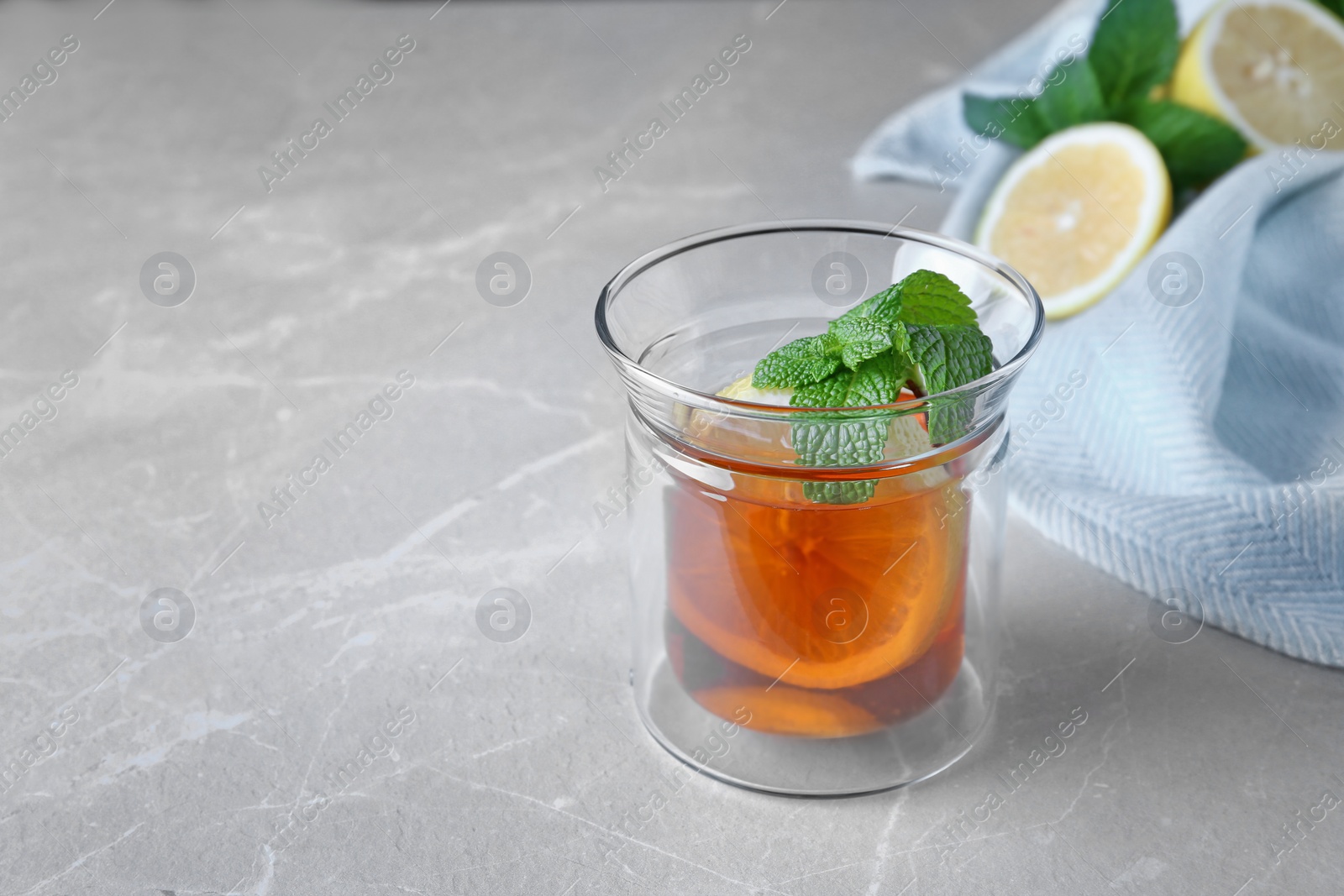 Photo of Hot tea with mint and lemon in glass on grey table. Space for text