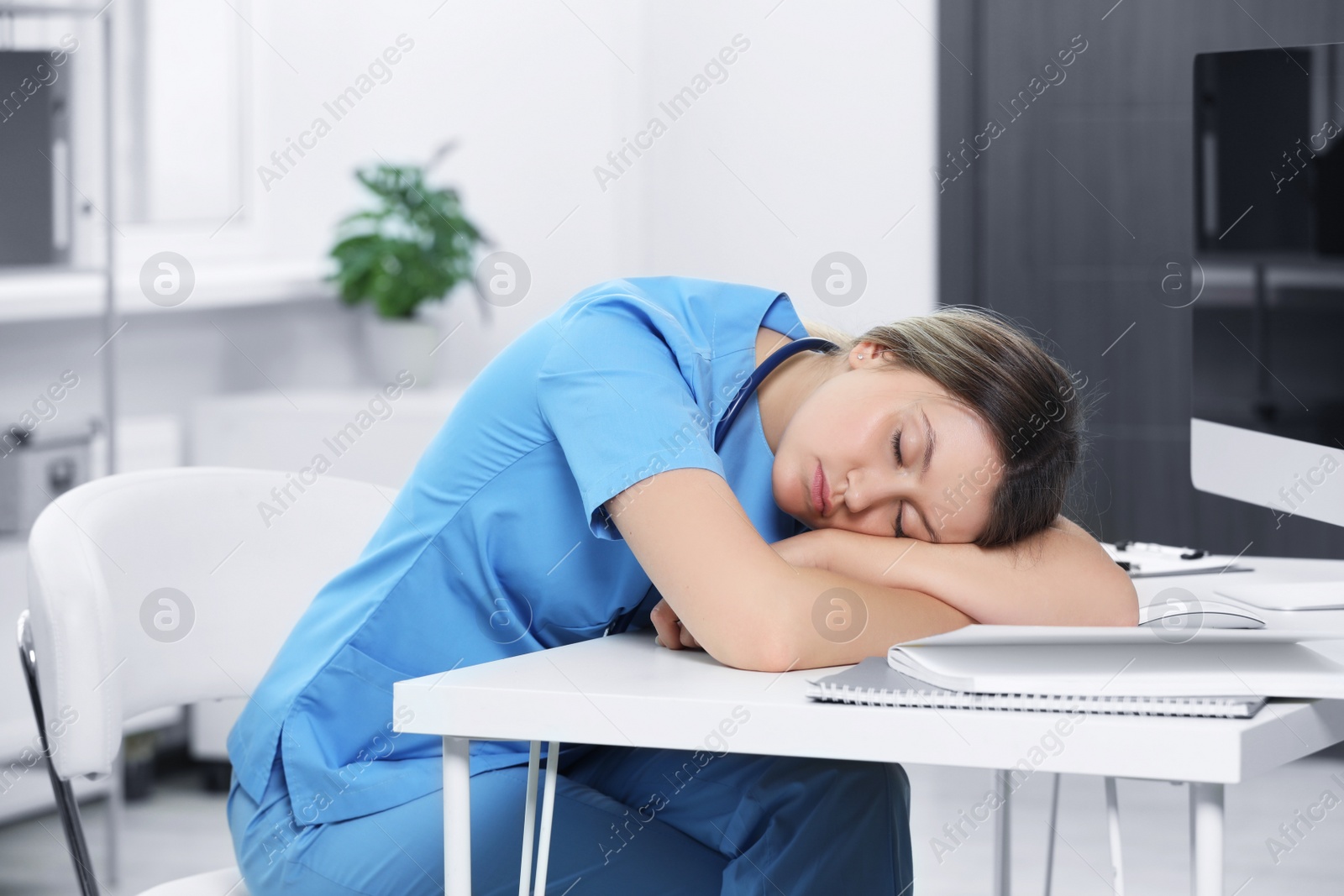 Photo of Exhausted doctor sleeping at workplace in hospital