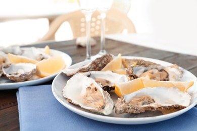 Photo of Fresh oysters with cut juicy lemon served on table