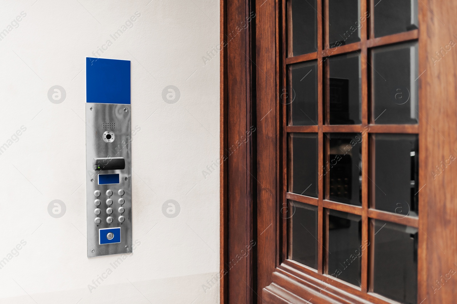 Photo of Modern intercom on white wall near door outdoors