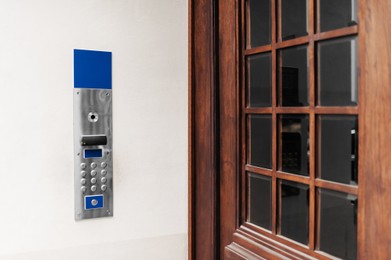 Photo of Modern intercom on white wall near door outdoors