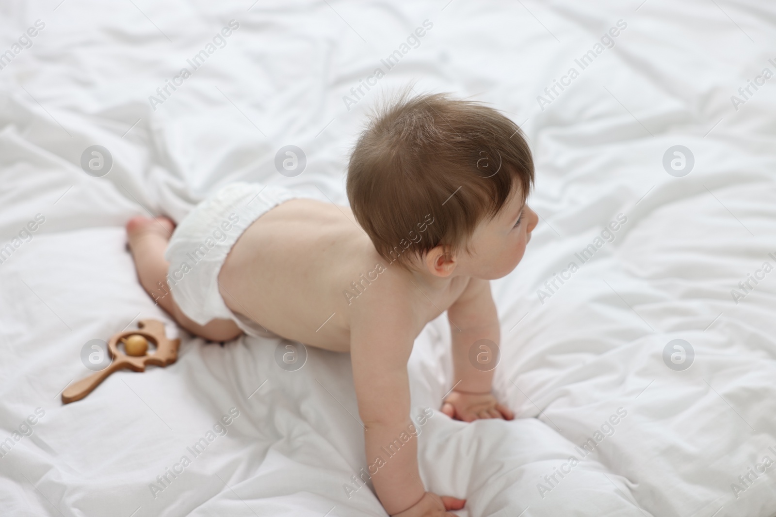 Photo of Baby boy in diaper crawling on bed