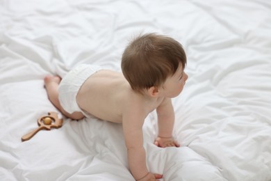 Baby boy in diaper crawling on bed