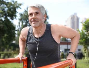 Photo of Handsome mature man doing exercise on sports ground. Healthy lifestyle