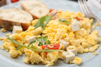 Photo of Delicious scrambled eggs, tofu and slices of baguette on plate, closeup