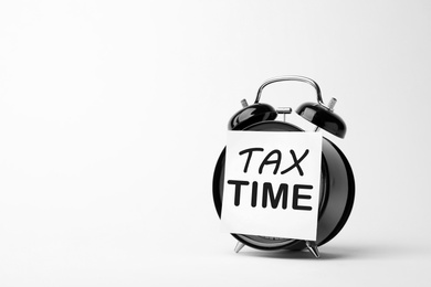 Image of Time to pay taxes. Alarm clock with sticky note on white background