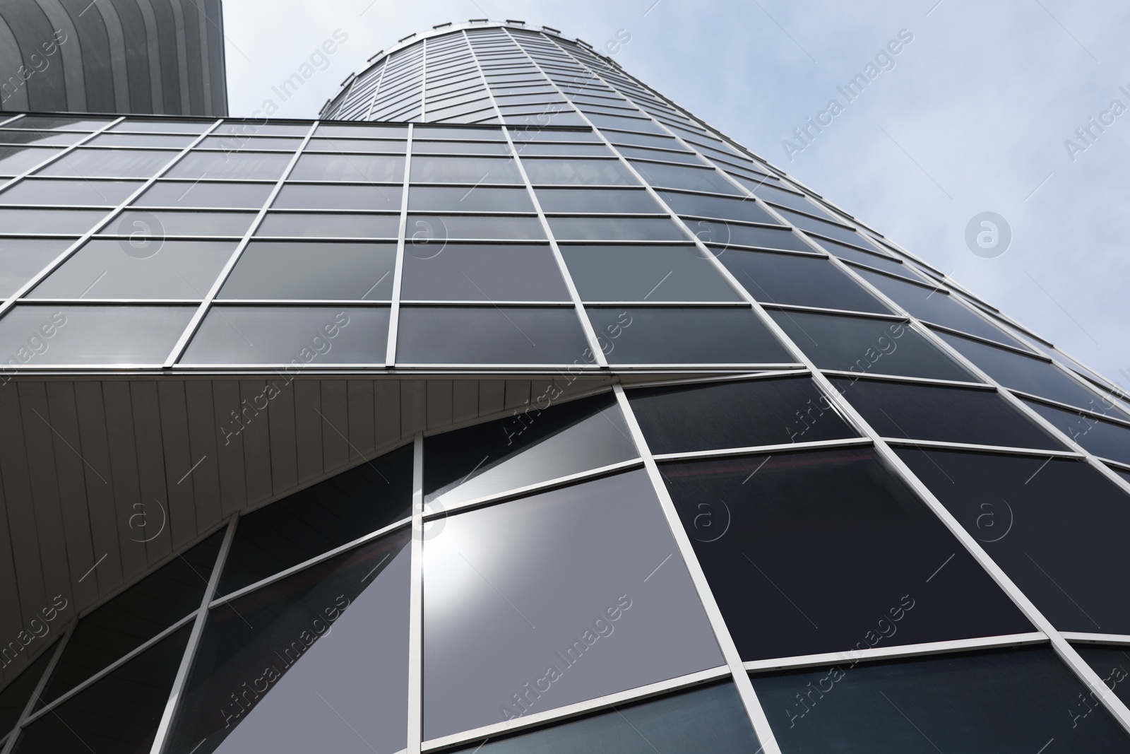 Photo of Modern building with tinted windows against sky, low angle view. Urban architecture