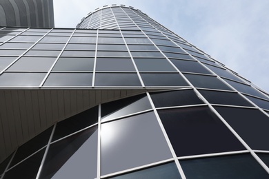 Modern building with tinted windows against sky, low angle view. Urban architecture