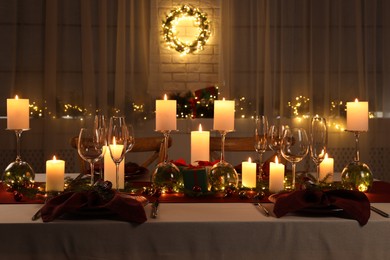 Photo of Christmas table setting with burning candles and festive decor