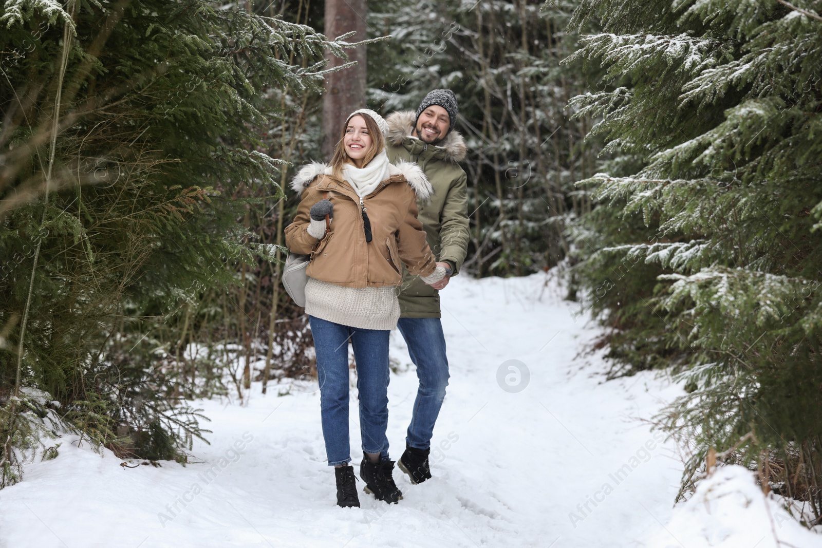 Photo of Couple in conifer forest on snowy day. Winter vacation