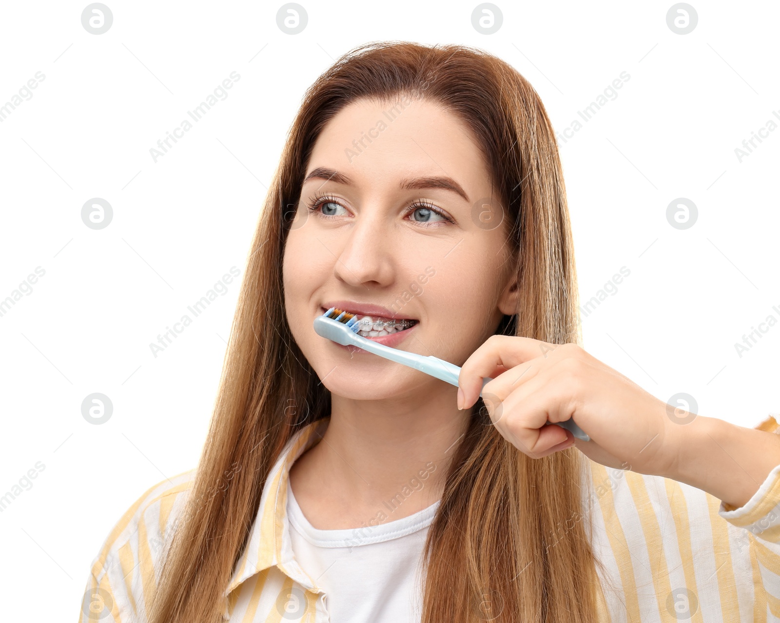 Photo of Smiling woman with dental braces cleaning teeth on white background