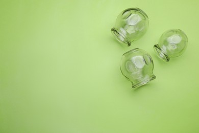Photo of Glass cups on light green background, flat lay and space for text. Cupping therapy