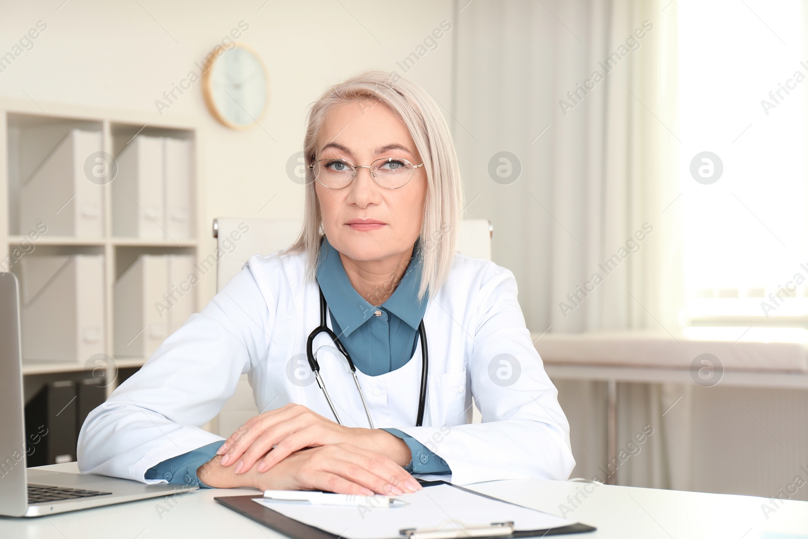 Photo of Portrait of mature female doctor in white coat at workplace