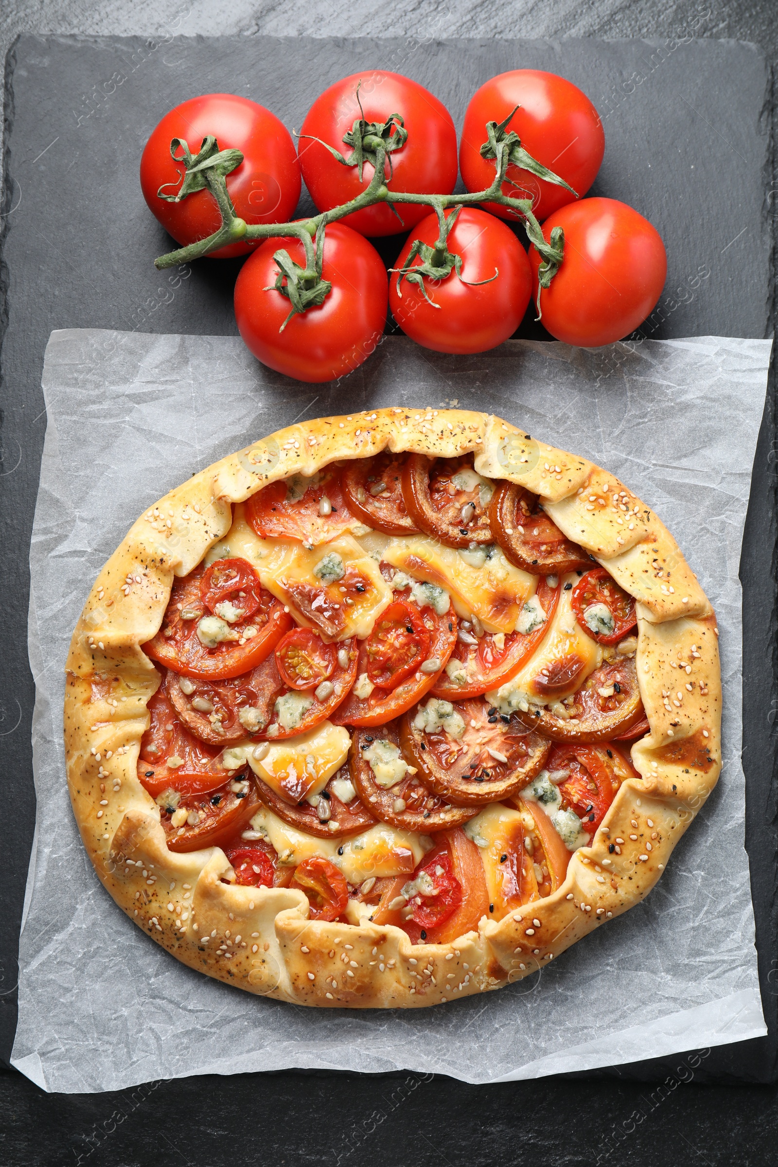 Photo of Tasty galette with tomato and cheese (Caprese galette) on dark table, top view