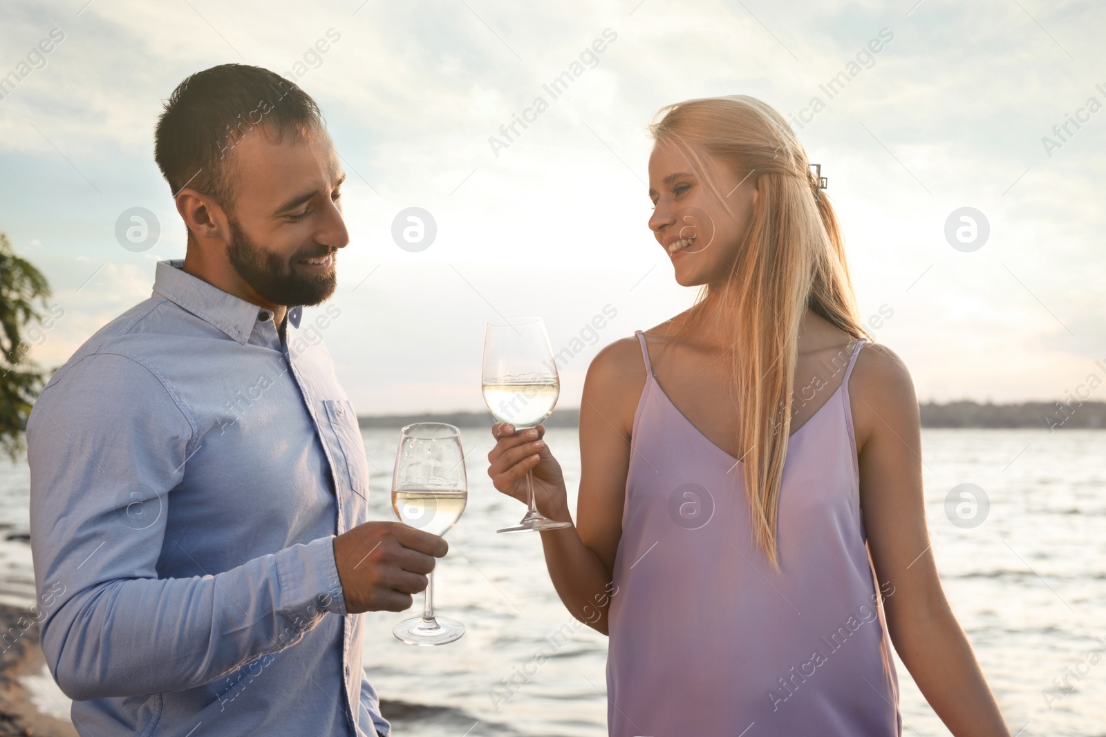 Photo of Couple with glasses near river at summer party