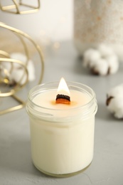 Burning candle with wooden wick on grey table