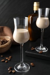 Photo of Coffee cream liqueur in glasses and beans on black wooden table