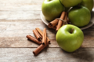 Fresh apples and cinnamon sticks on wooden table