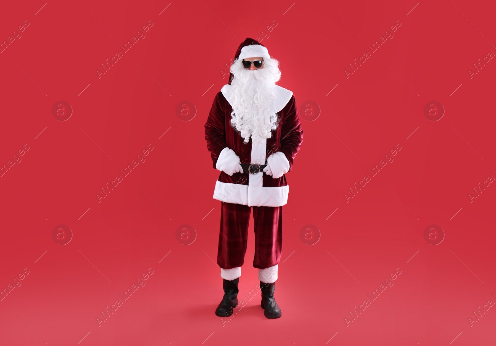 Photo of Full length portrait of Santa Claus with sunglasses on red background