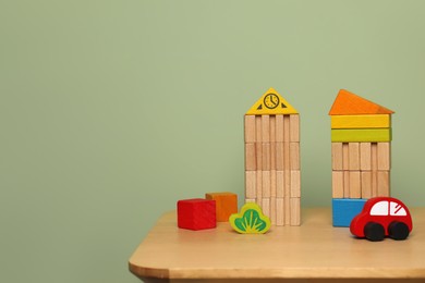 Photo of Set of different wooden toys on table near olive wall, space for text. Children's development