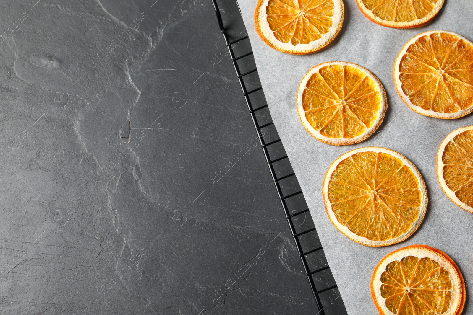 Photo of Dry orange slices on black table, top view. Space for text