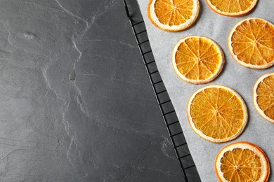 Photo of Dry orange slices on black table, top view. Space for text