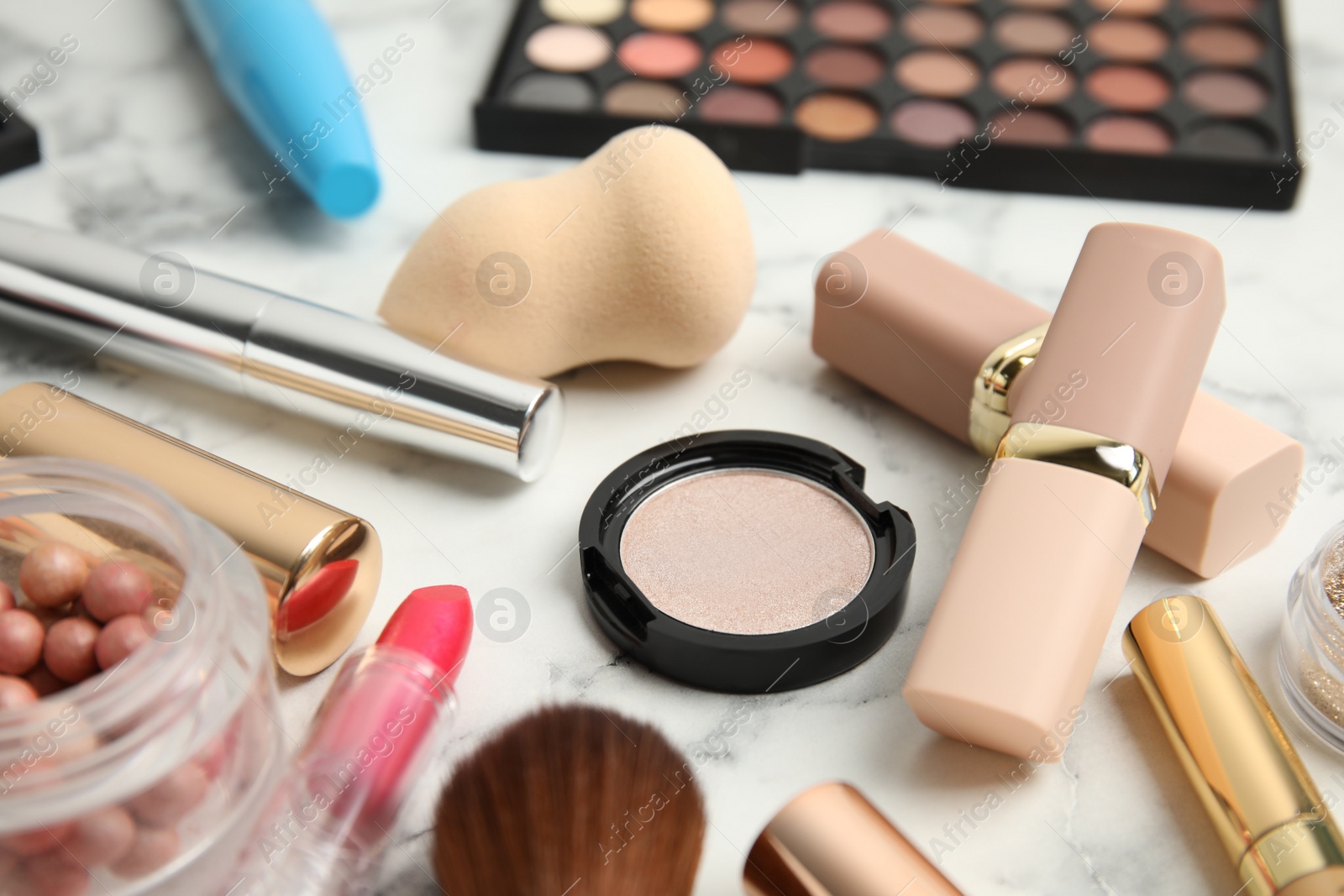 Photo of Different cosmetic products and makeup accessories on white marble table